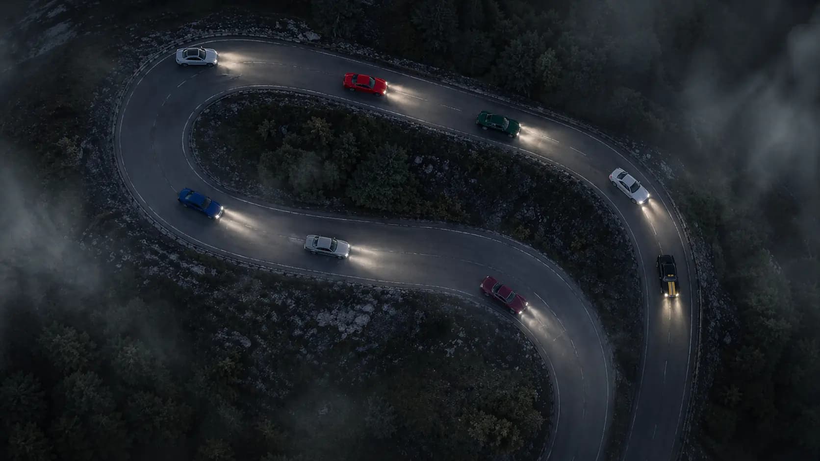Drone convoy through switchback at dusk.